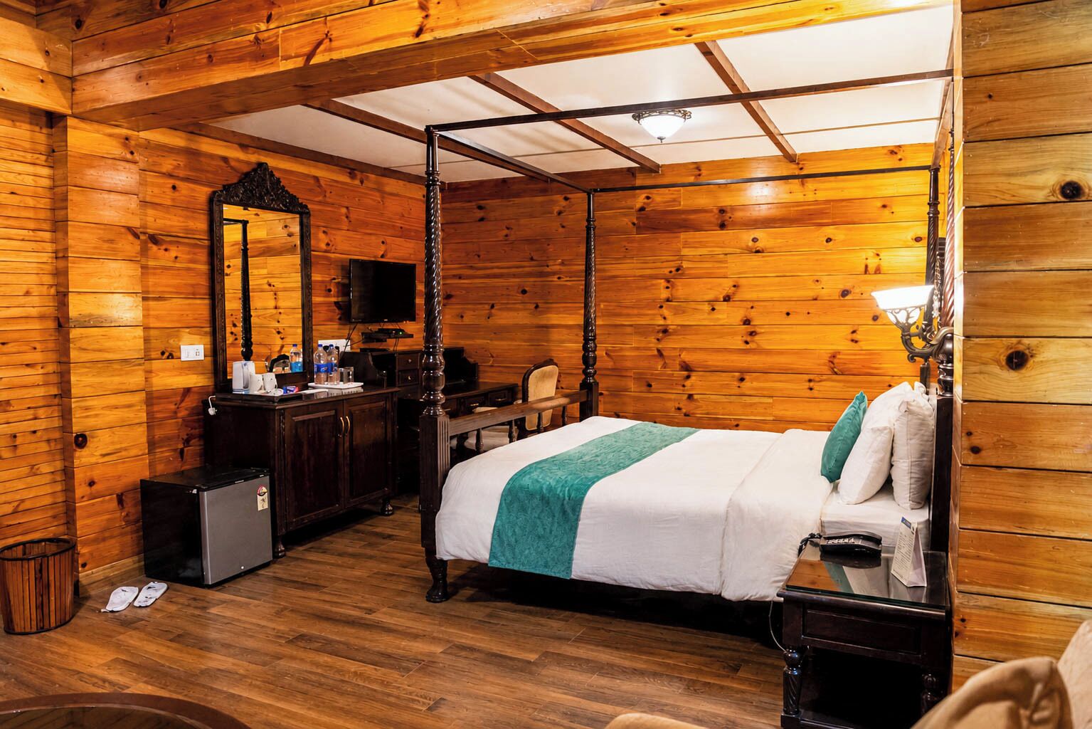 Una habitación con paneles de madera, una cama con dosel, un escritorio con computadora y un espejo grande.