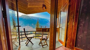 A wooden interior with a view of mountains through large glass doors.