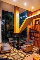 Una sala de estar moderna con un ventanal grande, una escalera original y una colección de objetos decorativos.