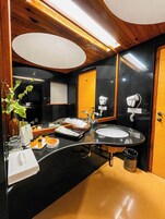 Un bagno moderno con un lavabo nero, uno specchio e un mobile bagno in legno.