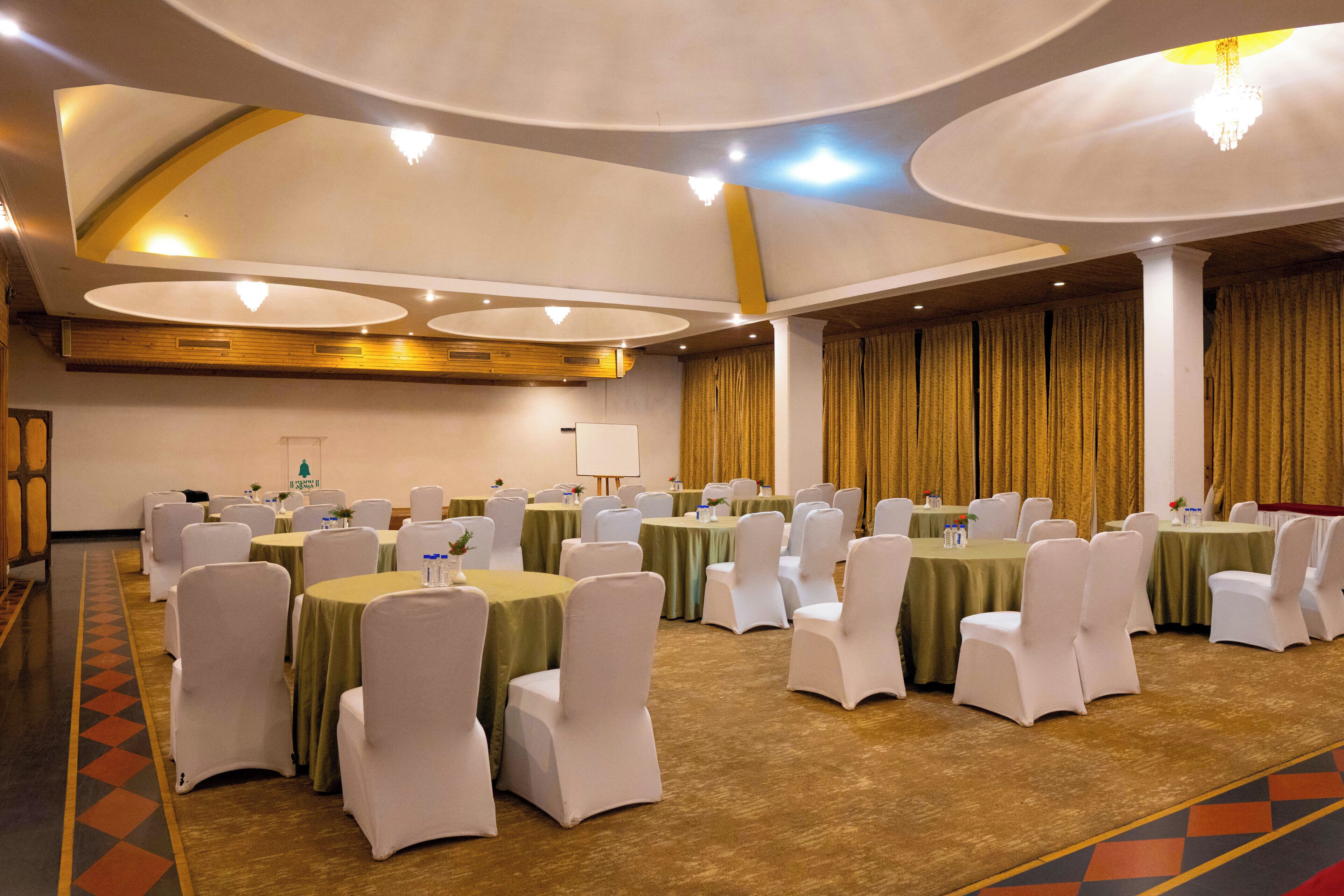 A conference room with multiple tables and chairs, a whiteboard, and a chandelier.