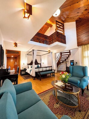 A spacious living area with a high ceiling, a wooden staircase, a bed with a canopy, a piano, and a blue armchair. - Manuallaya The Resort Spa in the Himalayas (Manali)