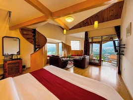 Amplia habitación con una cama grande, una escalera, zona de estar con vistas y un balcón.