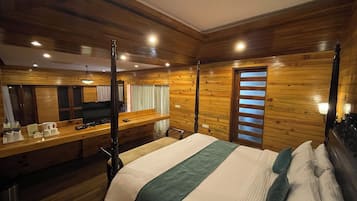 A wooden-paneled room with a bed, a desk, and a television.