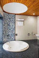 A modern bathroom with a freestanding bathtub, a shower area, and a tiled wall with a mosaic pattern.