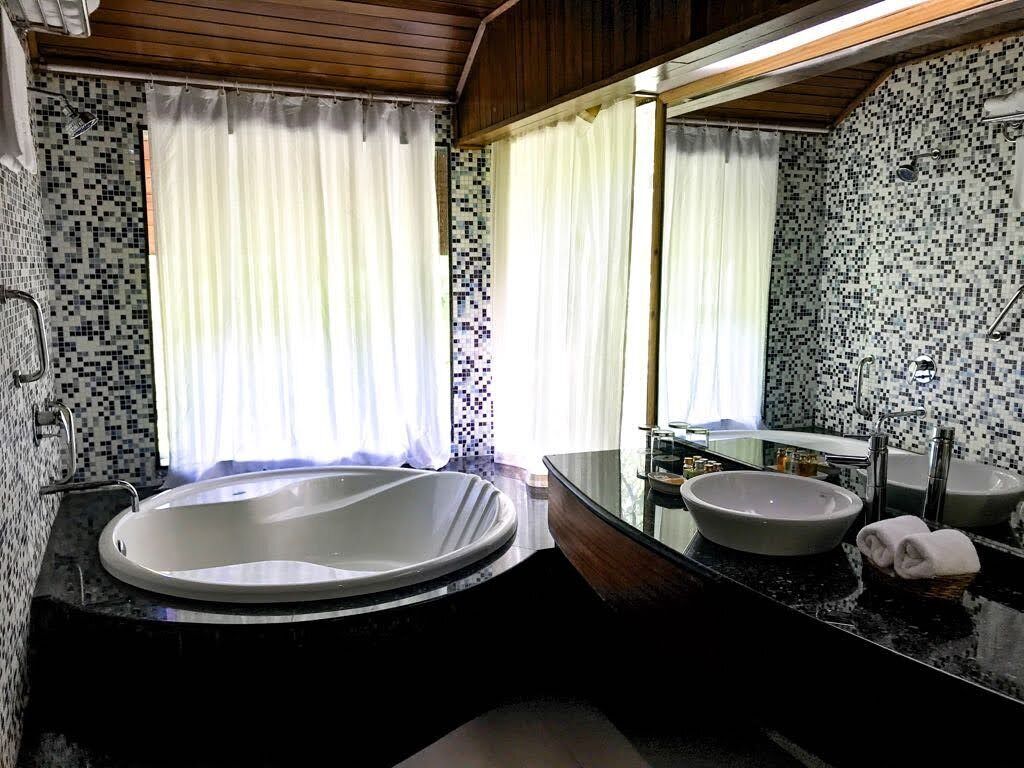 A bathroom with a large bathtub, two sinks, and a mirror.