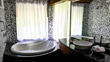 A bathroom with a large bathtub, two sinks, and a mirror.