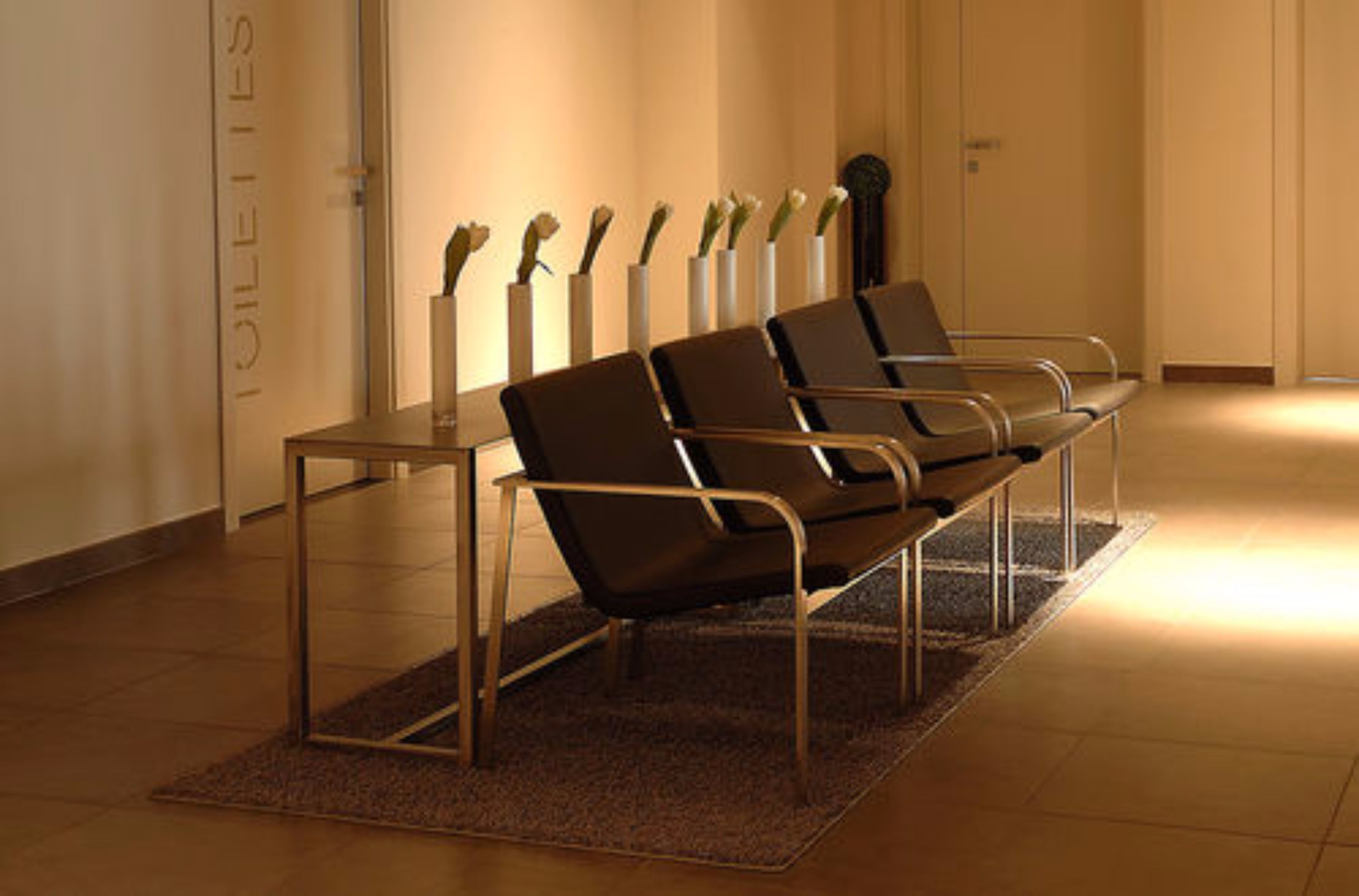 A waiting area with a bench and a table, a wall with a sign, and a door.