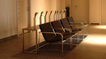 Un área de espera con un banco y una mesa, una pared con un letrero y una puerta.