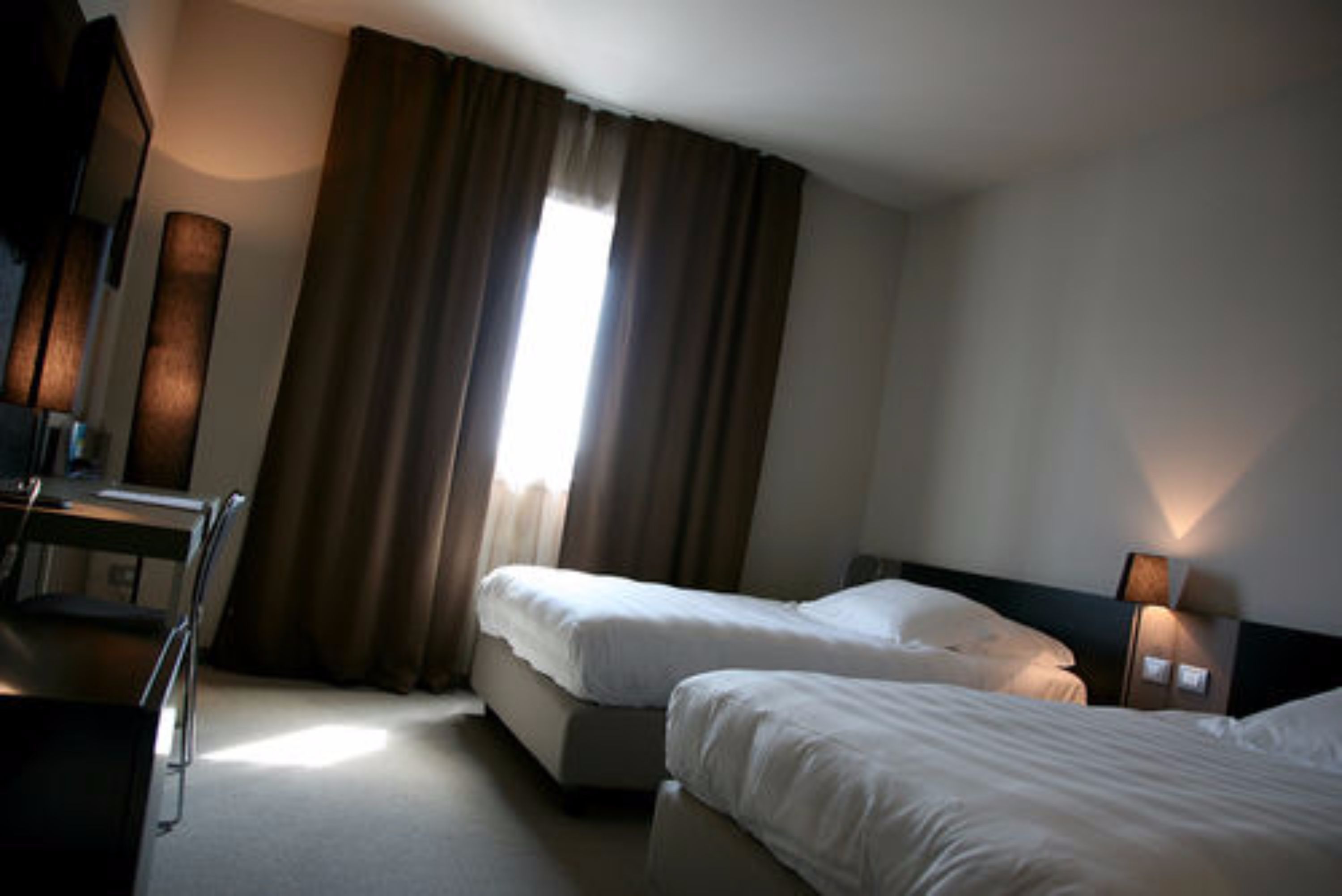 Habitación de hotel con dos camas, un escritorio y una silla.