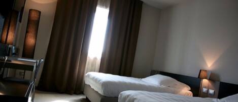 Habitación de hotel con dos camas, un escritorio y una silla.