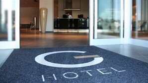 A hotel entrance with a carpeted area marked with a large 'H' and the word 'HOTEL' in white letters.
