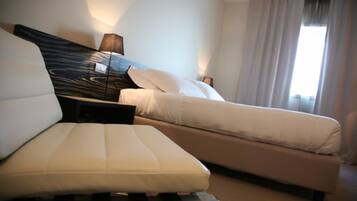 Una habitación de hotel con una cama, un sofá, una lámpara y una ventana con cortinas.
