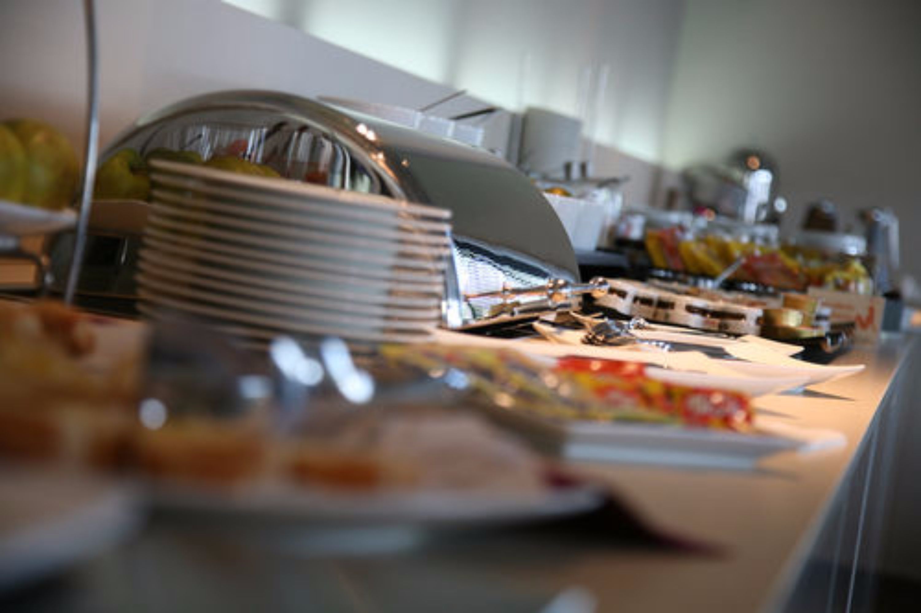 A buffet setup with various food items and a stack of plates.