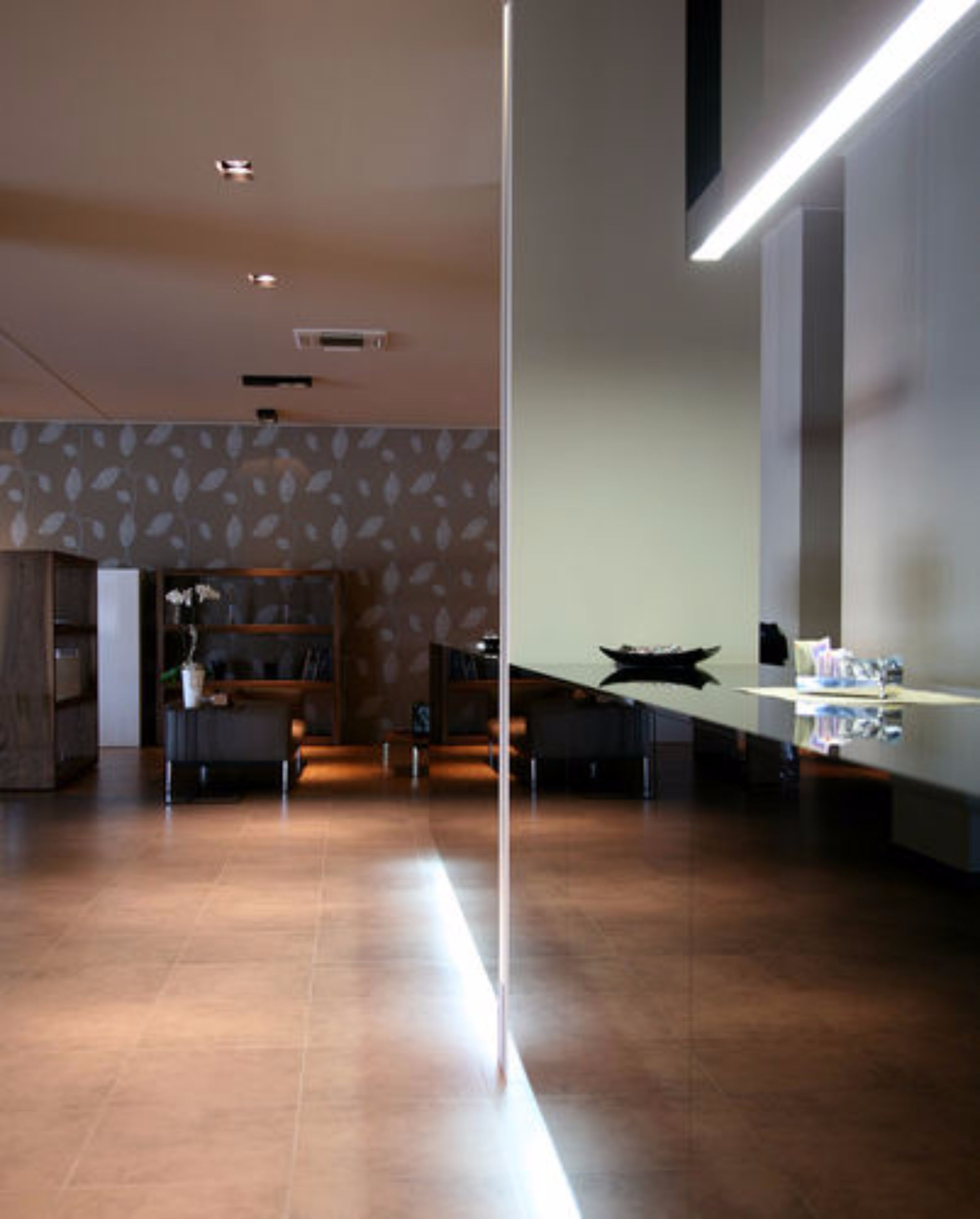 A modern kitchen with a long countertop, wooden cabinets, and a decorative wall with leaf patterns.