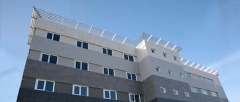 Un edificio de varios pisos con un diseño arquitectónico moderno, que cuenta con una serie de balcones y ventanas.