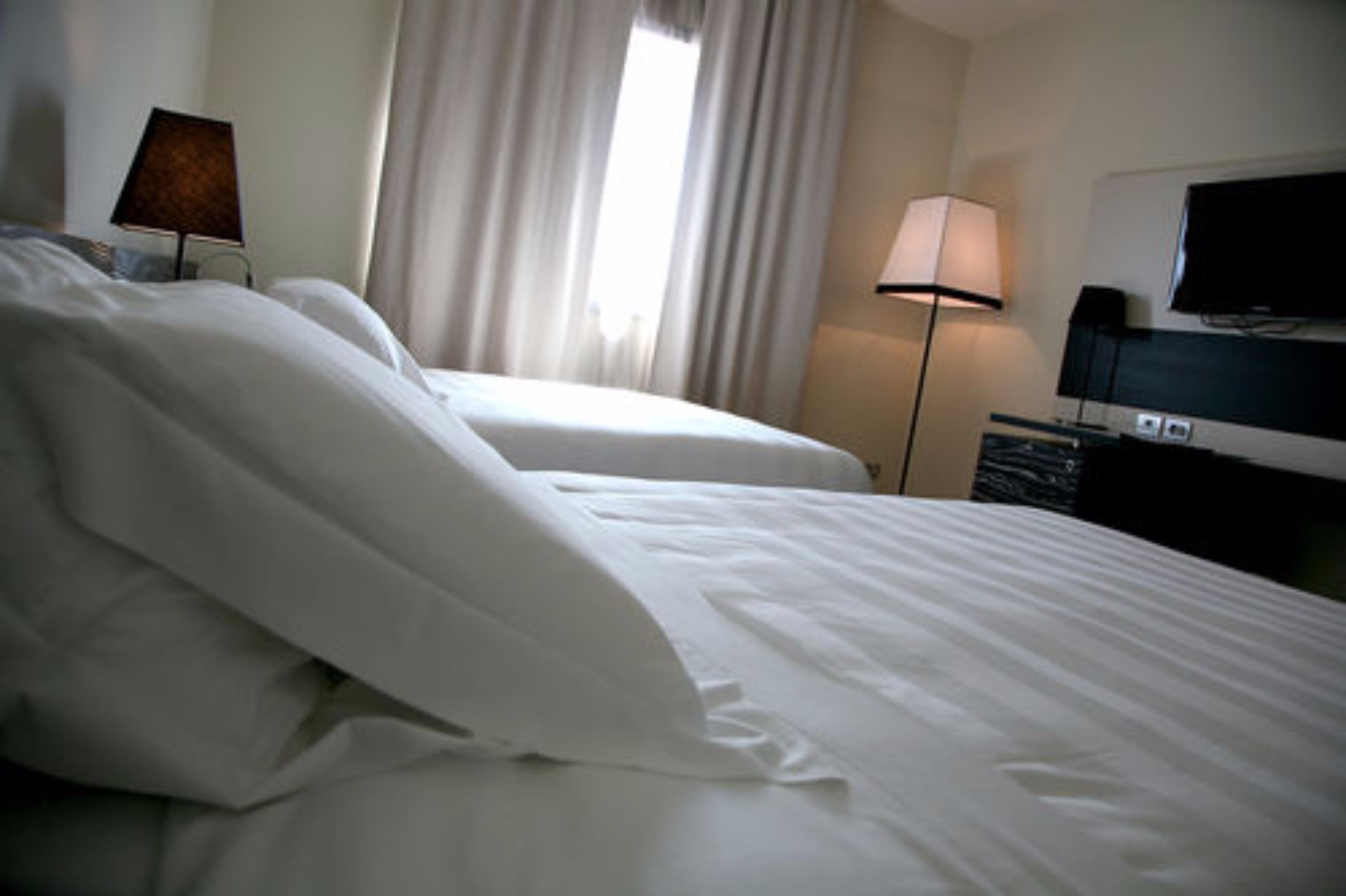 Una habitación de hotel con dos camas, televisión y lámpara.
