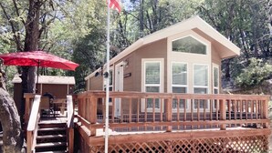 Eine Holzhütte mit einer Holzterrasse, einem roten Sonnenschirm und einer Flagge.