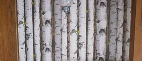 A room with a wooden-framed window, a white furry rug, and a curtain with a birch tree pattern.