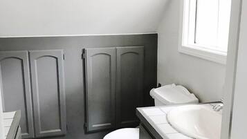 Un baño pequeño y funcional con inodoro, lavamanos y armarios de madera oscura.