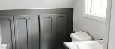 A small, compact bathroom with a toilet, sink, and dark wooden cabinets.