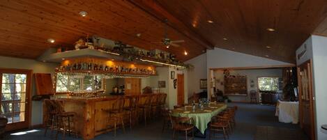 Un intérieur rustique avec un bar en bois, un coin repas et une grande fenêtre.