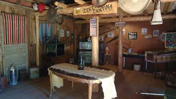 Cozy cabin-style interior with a central table, wooden walls, and eclectic decor.