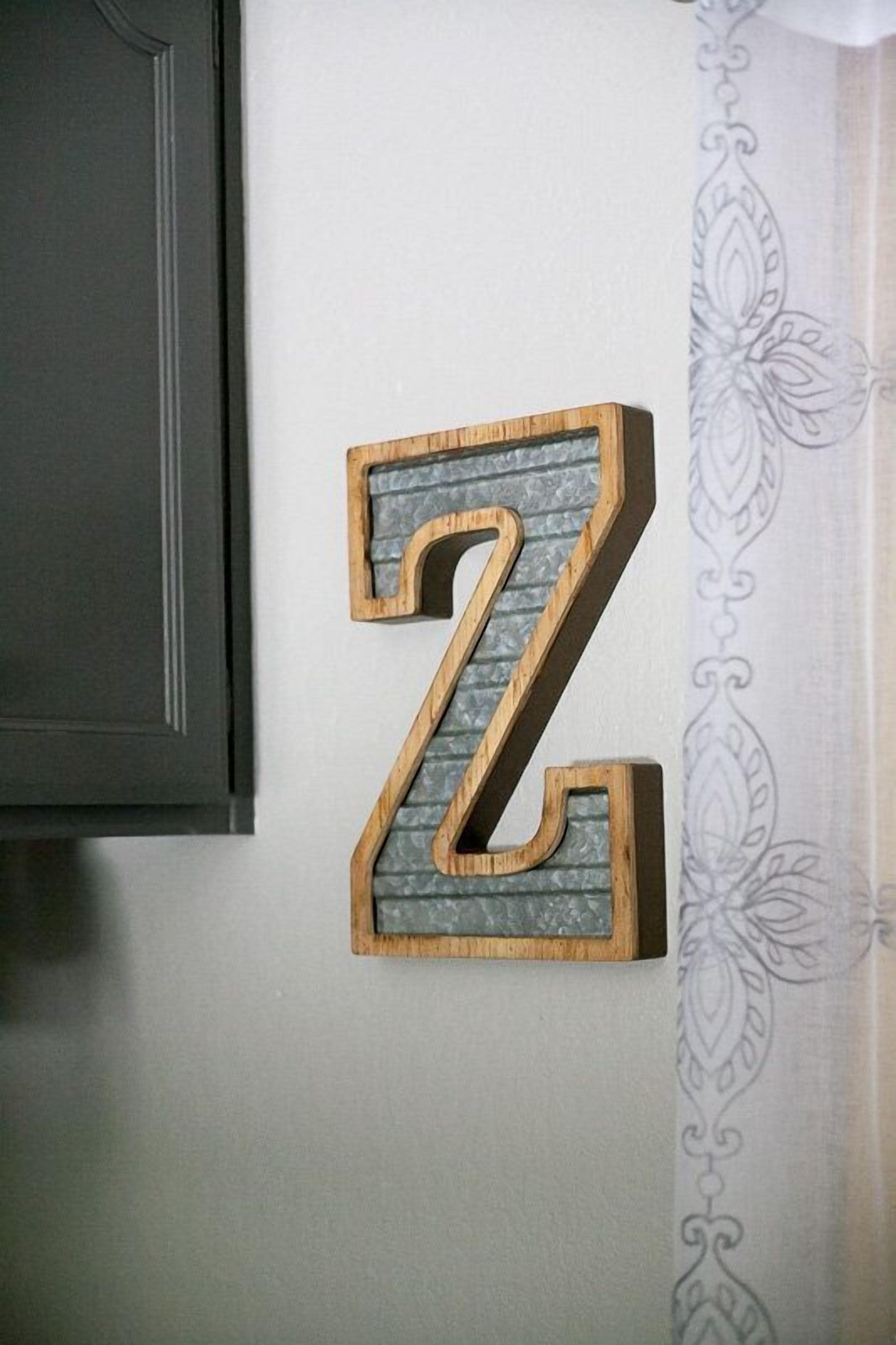 Une lettre Z en bois, avec un fond texturé, fixée au mur et agrémentée d’un rideau à motifs.