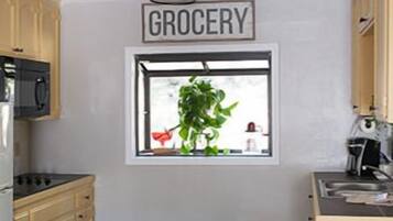 Una cocina con ventanal, un cartel que dice 'GROCERY' y una mesa con sillas.