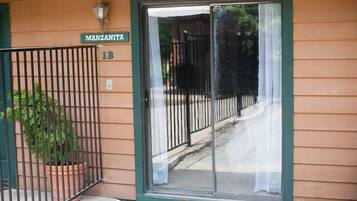A building entrance with a sliding glass door, a metal gate, and a potted plant.