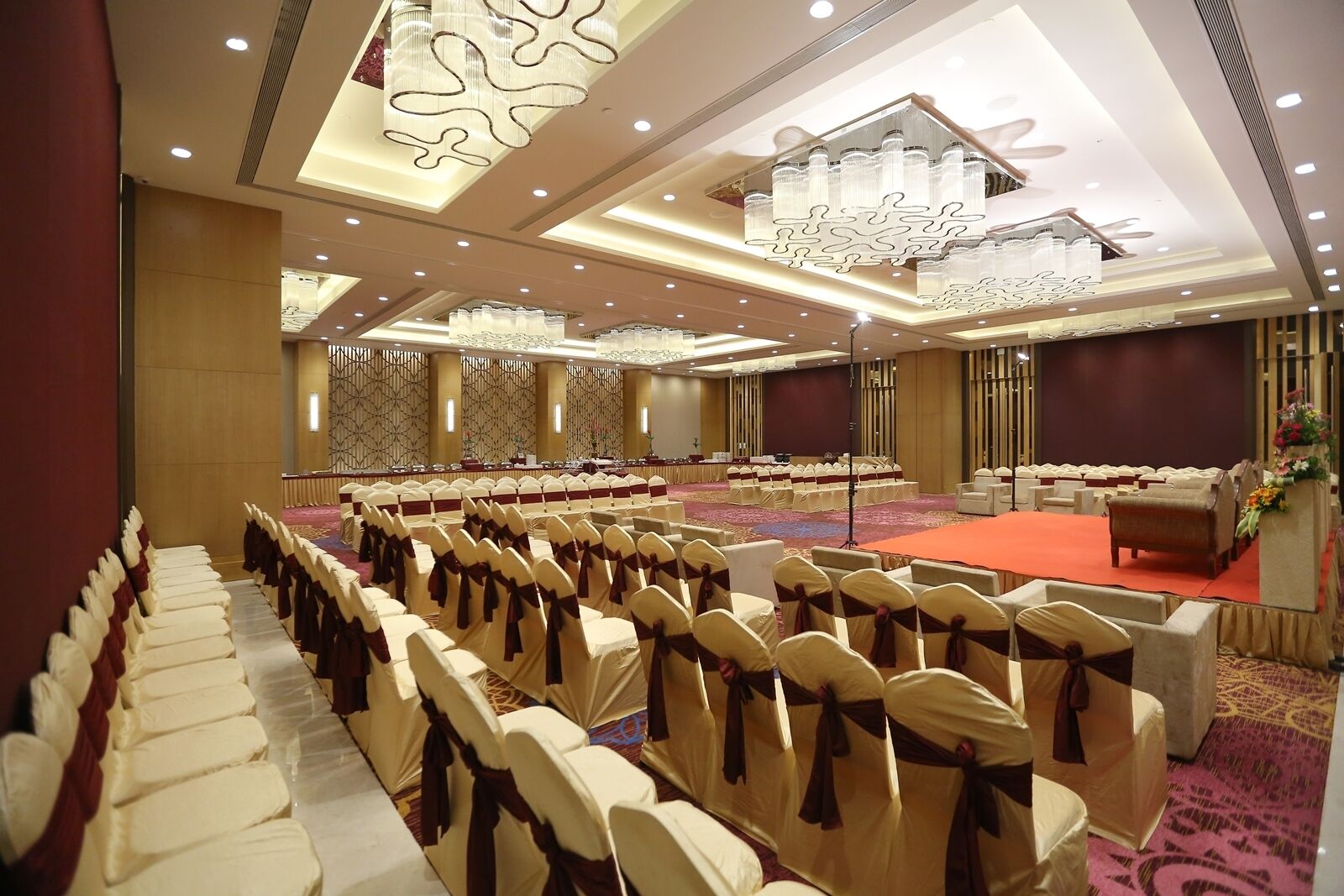 A large conference room with rows of chairs, a stage, and a carpeted floor.