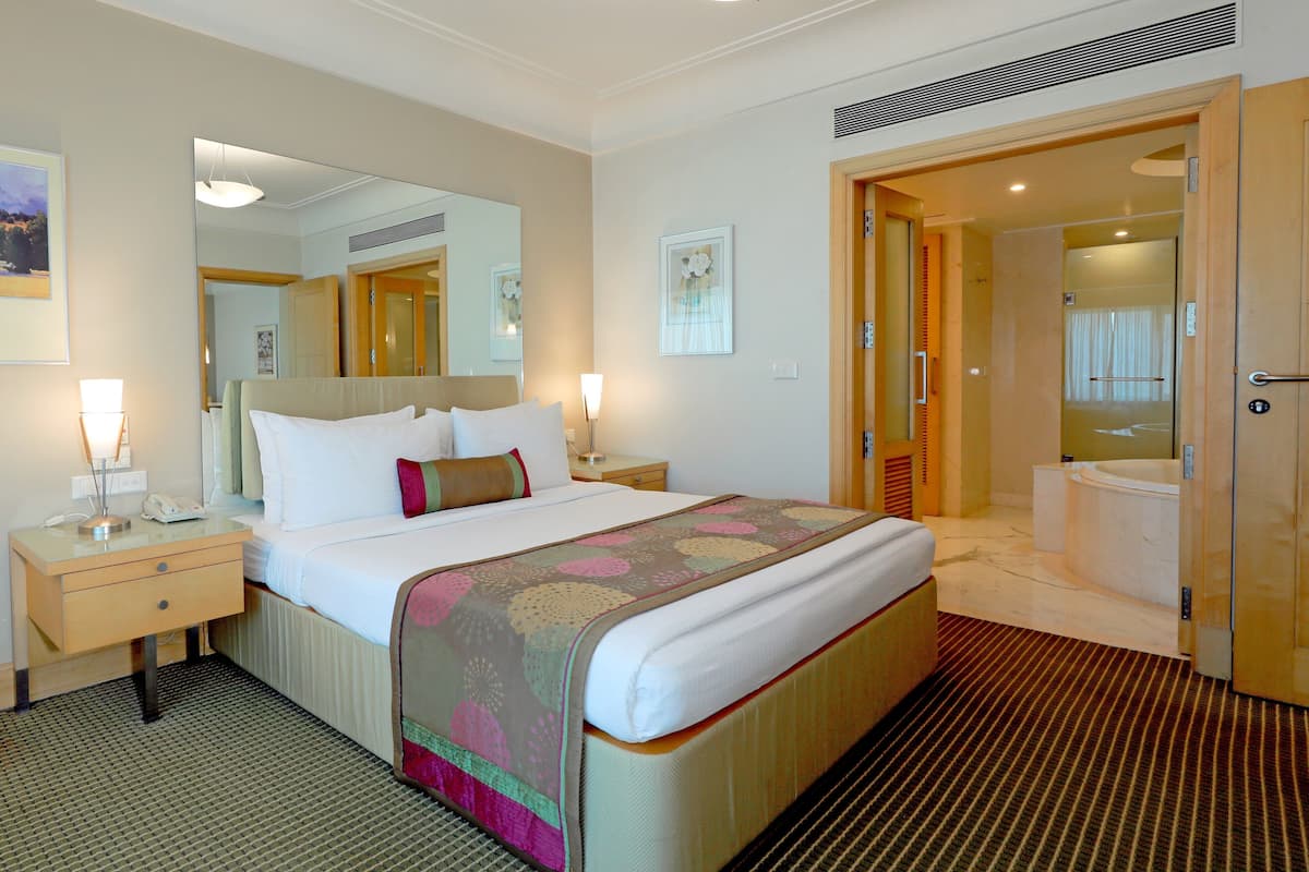 Ein Hotelzimmer mit einem großen Bett, Nachttischen, einem Spiegel und einem Badezimmer mit einer Badewanne.
