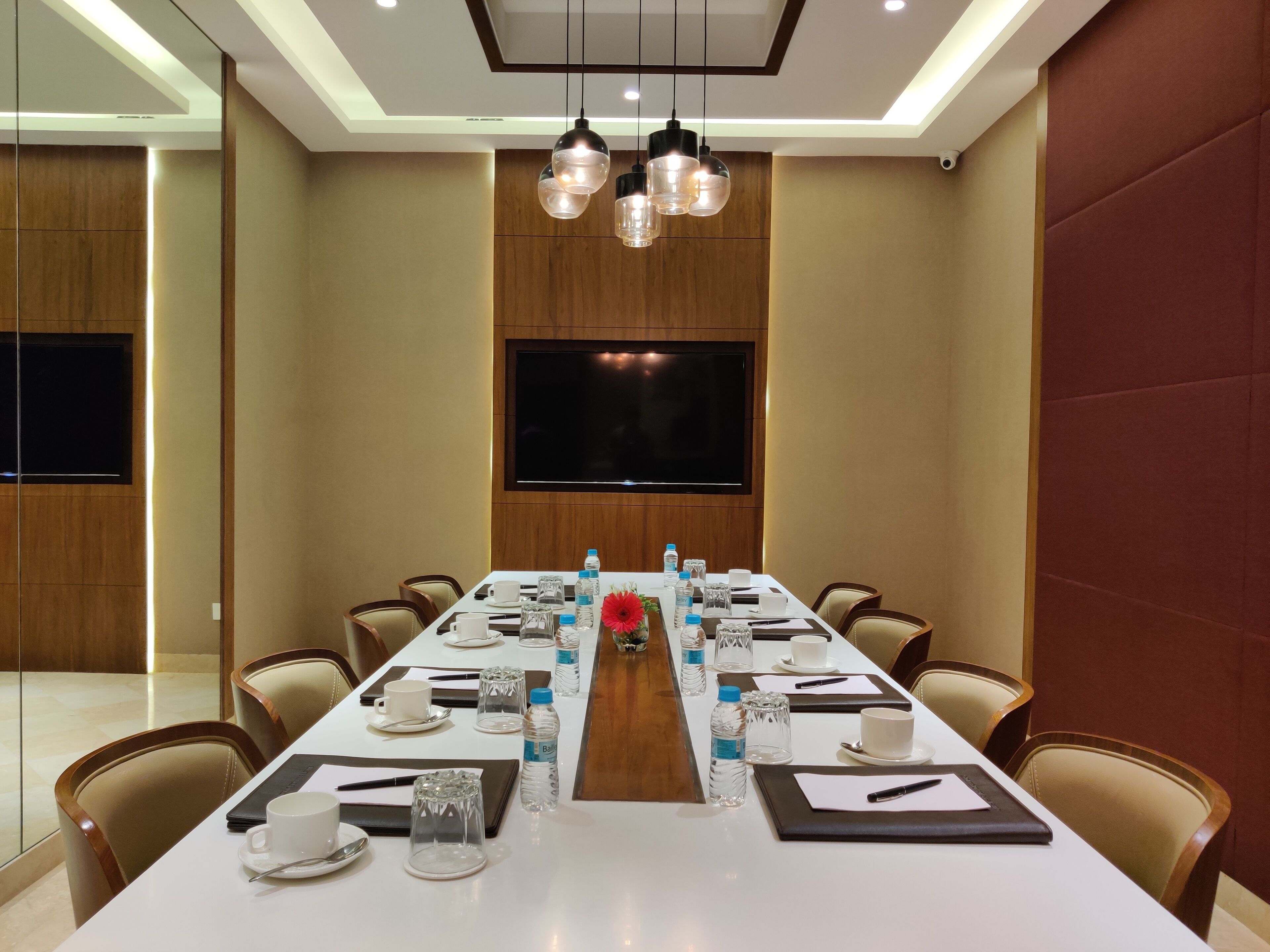 A conference room with a long table, chairs, a TV screen, and water bottles.