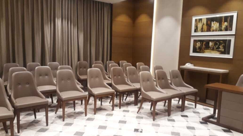 A conference room with rows of chairs, a table, and a large curtain.
