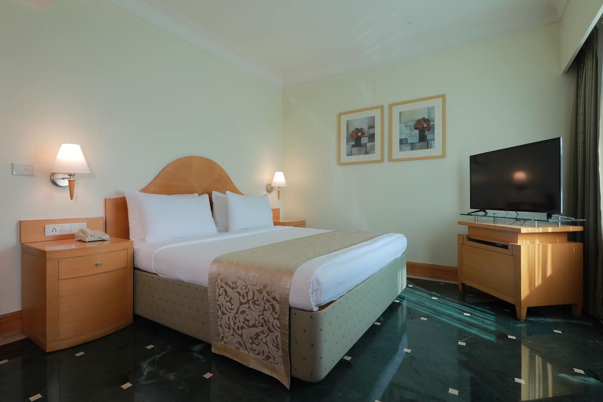 Ein Hotelzimmer mit Bett, Nachttischen, einem Fernseher und Bildern an der Wand.