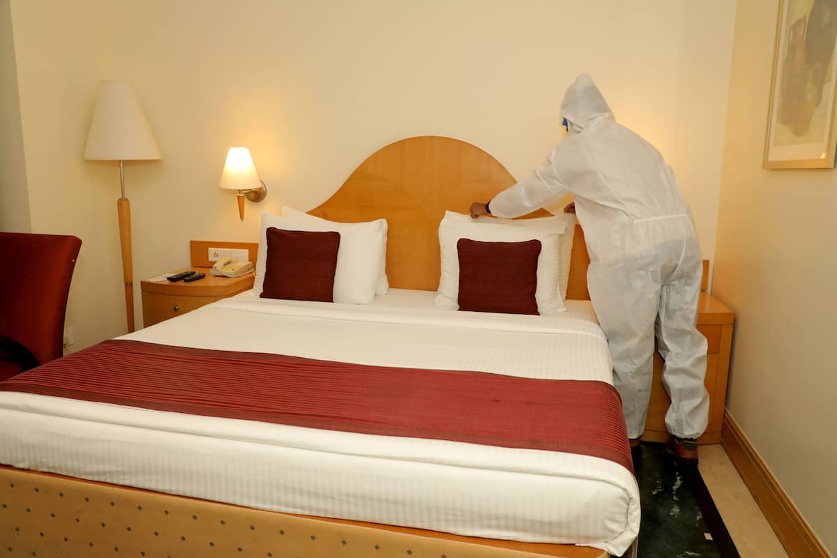 Ein Hotelzimmer mit einem ordentlich bezogenen Bett, einer Nachttischlampe, einem Telefon und einem Nachttisch.
