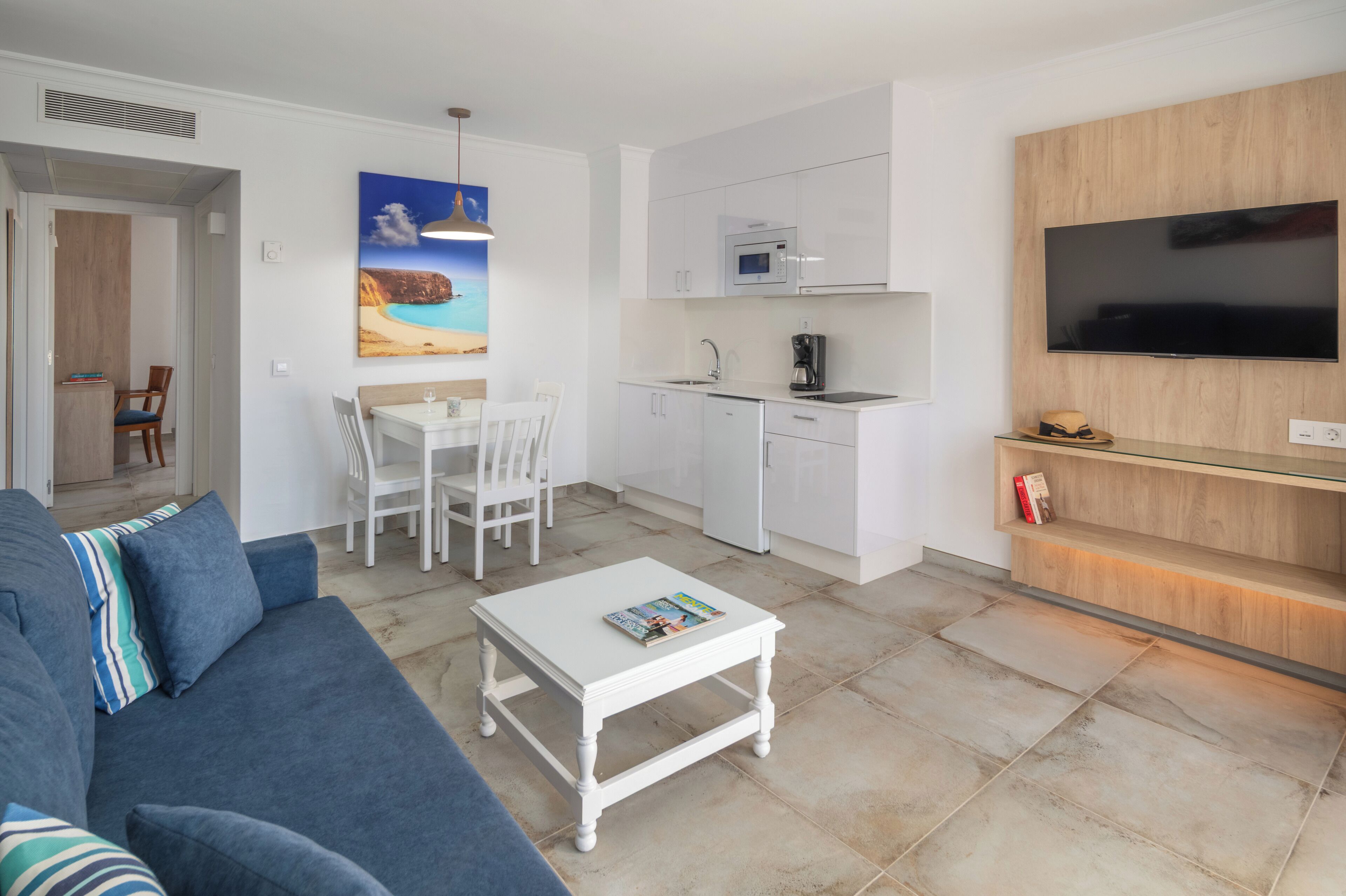 A compact living space with a kitchenette, a dining area, and a seating area with a sofa and coffee table.