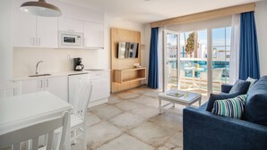 Ein modernes Hotelzimmer mit Essbereich, einem Wohnbereich mit Sofa, Fernseher und einem Balkon mit Blick auf den Pool.