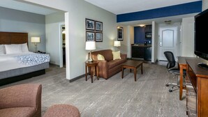 A hotel room with a bed, a sofa, a coffee table, a desk with a chair, and a television. - La Quinta Inn & Suites by Wyndham Horn Lake / Southaven Area (Horn Lake)
