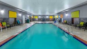 A large indoor swimming pool with clear blue water, surrounded by colorful chairs and a tiled floor. - La Quinta Inn & Suites by Wyndham Horn Lake / Southaven Area (Horn Lake)