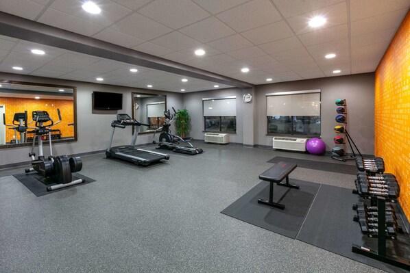 Un gimnasio con cintas de correr, máquinas de pesas y pelotas de ejercicio.