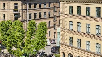 Une vue de rue avec une rangée de bâtiments, des arbres et des voitures garées.
