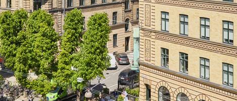 Vista de una calle con edificios, árboles y coches estacionados.