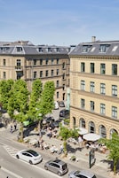 Vista de una calle con edificios, árboles y coches estacionados.
