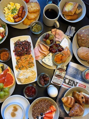 A breakfast spread with various foods and a newspaper. - Hotel Sct Thomas (Frederiksberg)