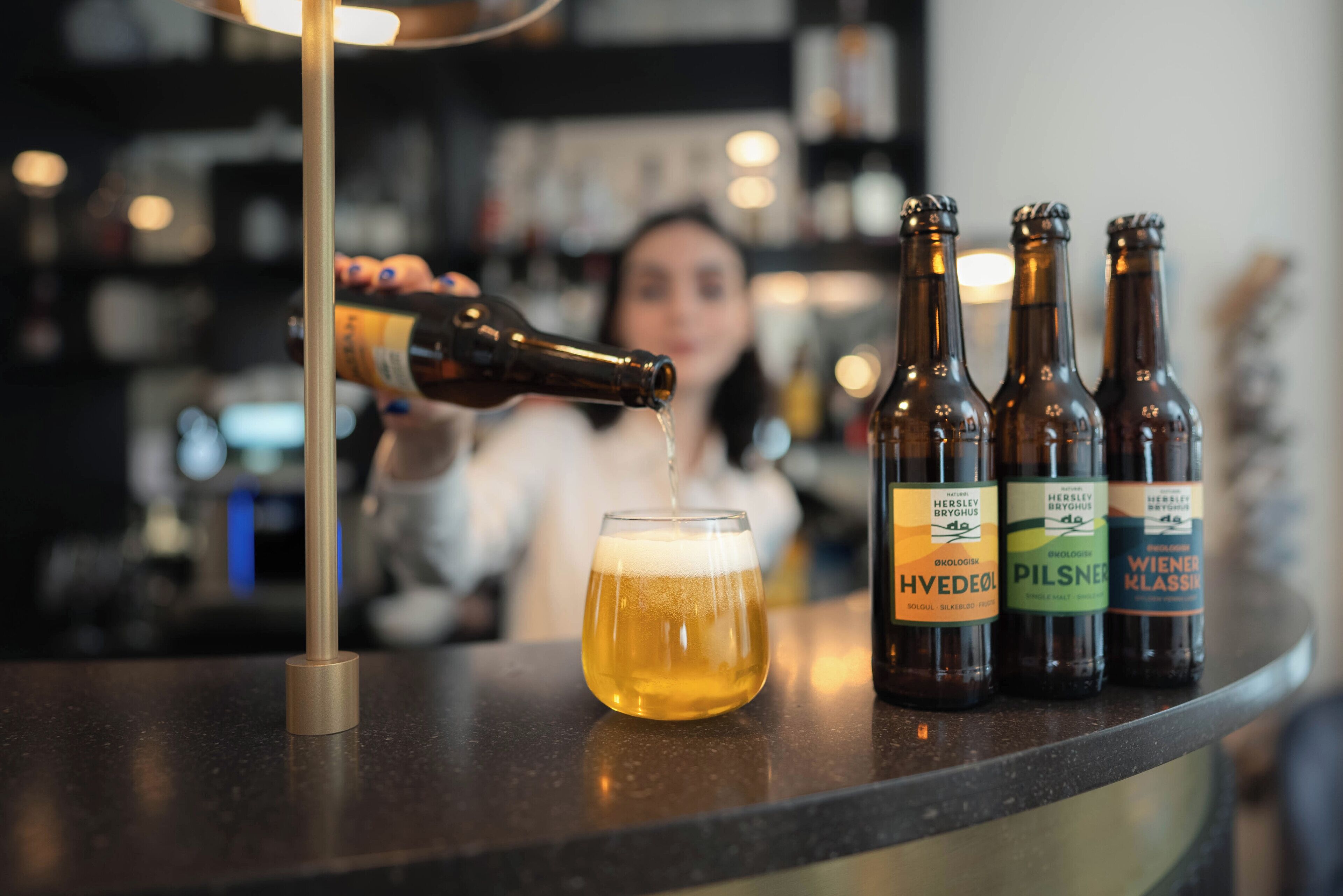Una barra con botellas de cerveza y una copa siendo servida.