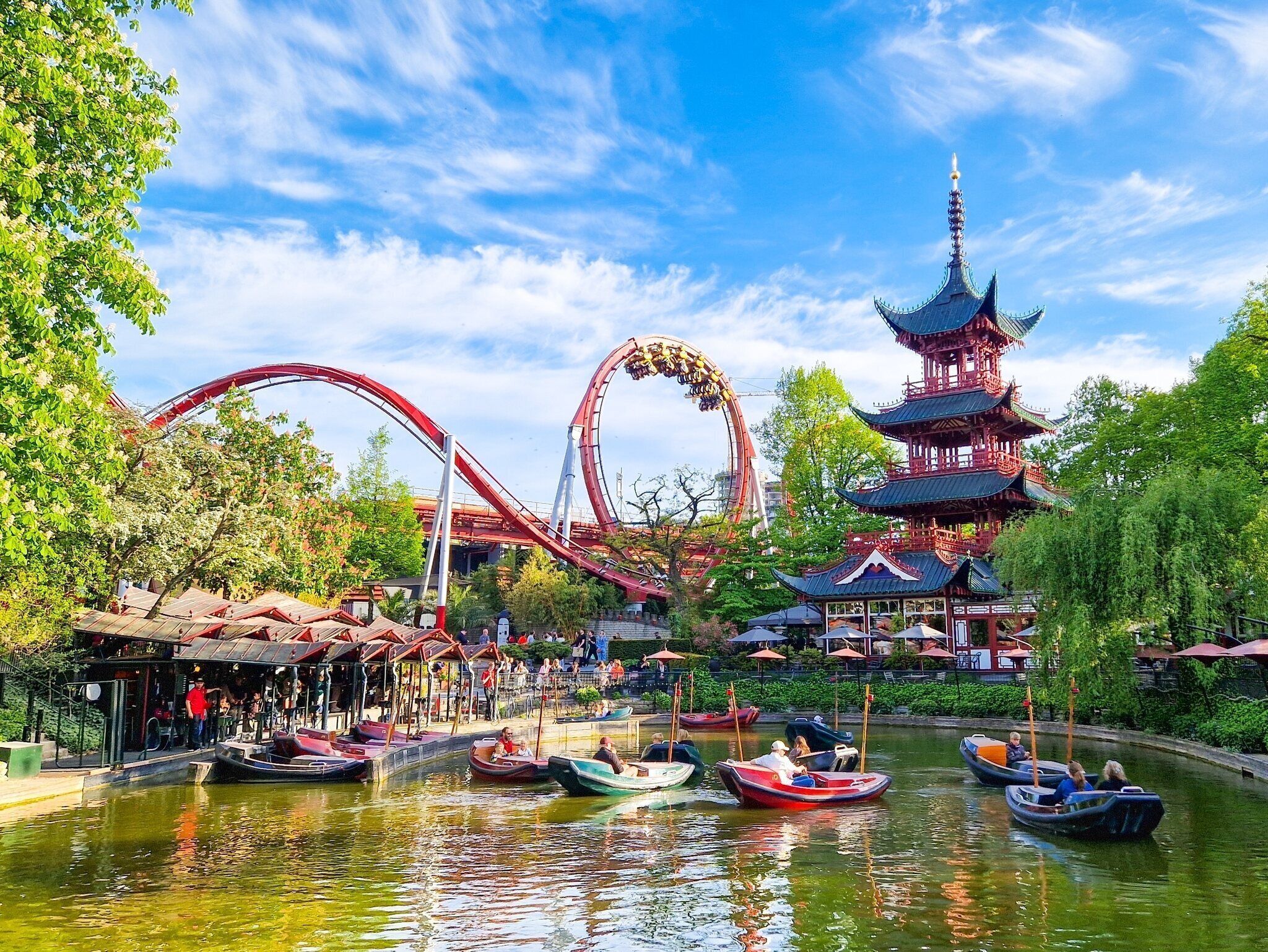 Parque acuático con una montaña rusa, una pagoda tradicional y barcos.
