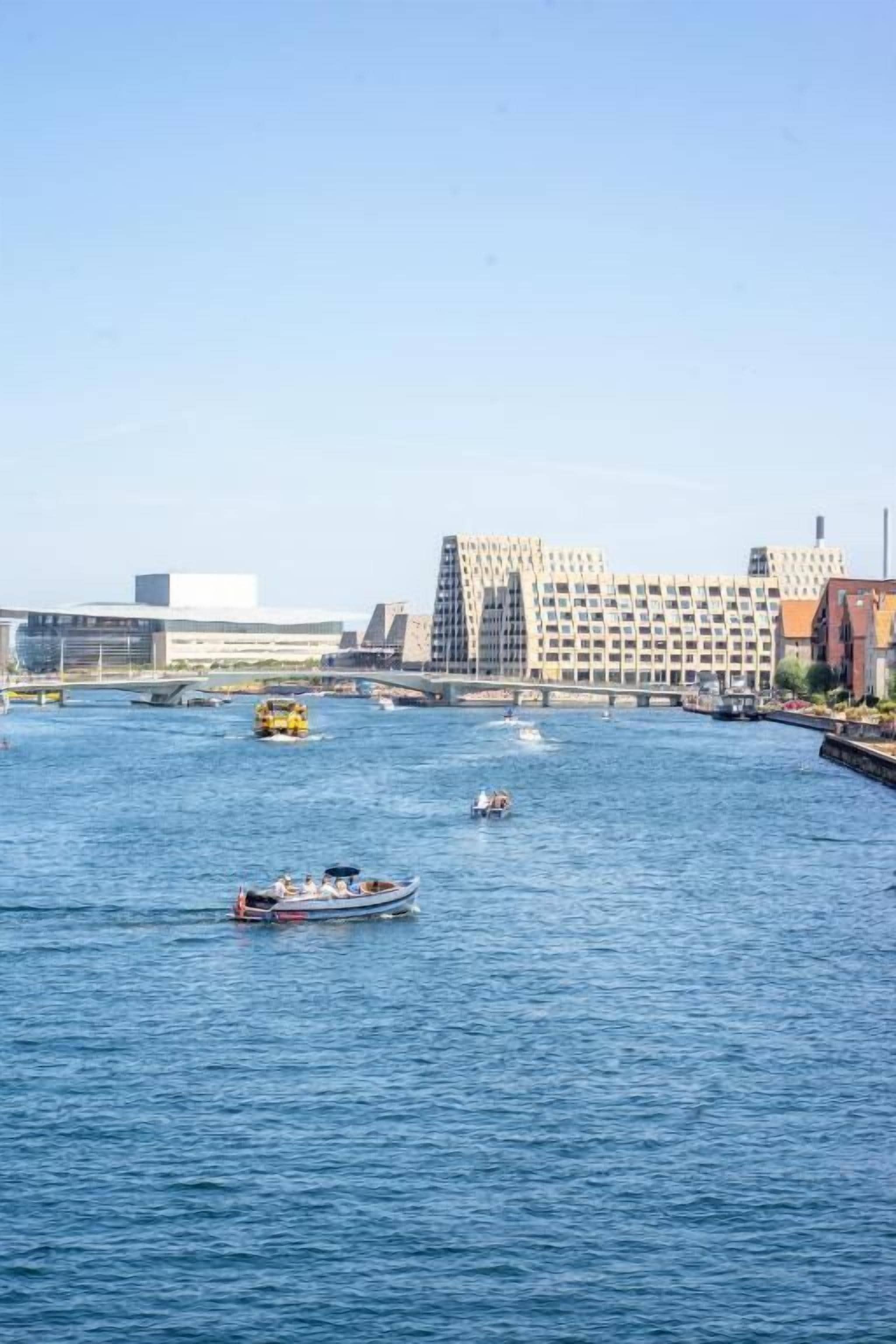 Un río con barcos y un edificio moderno al otro lado del agua.
