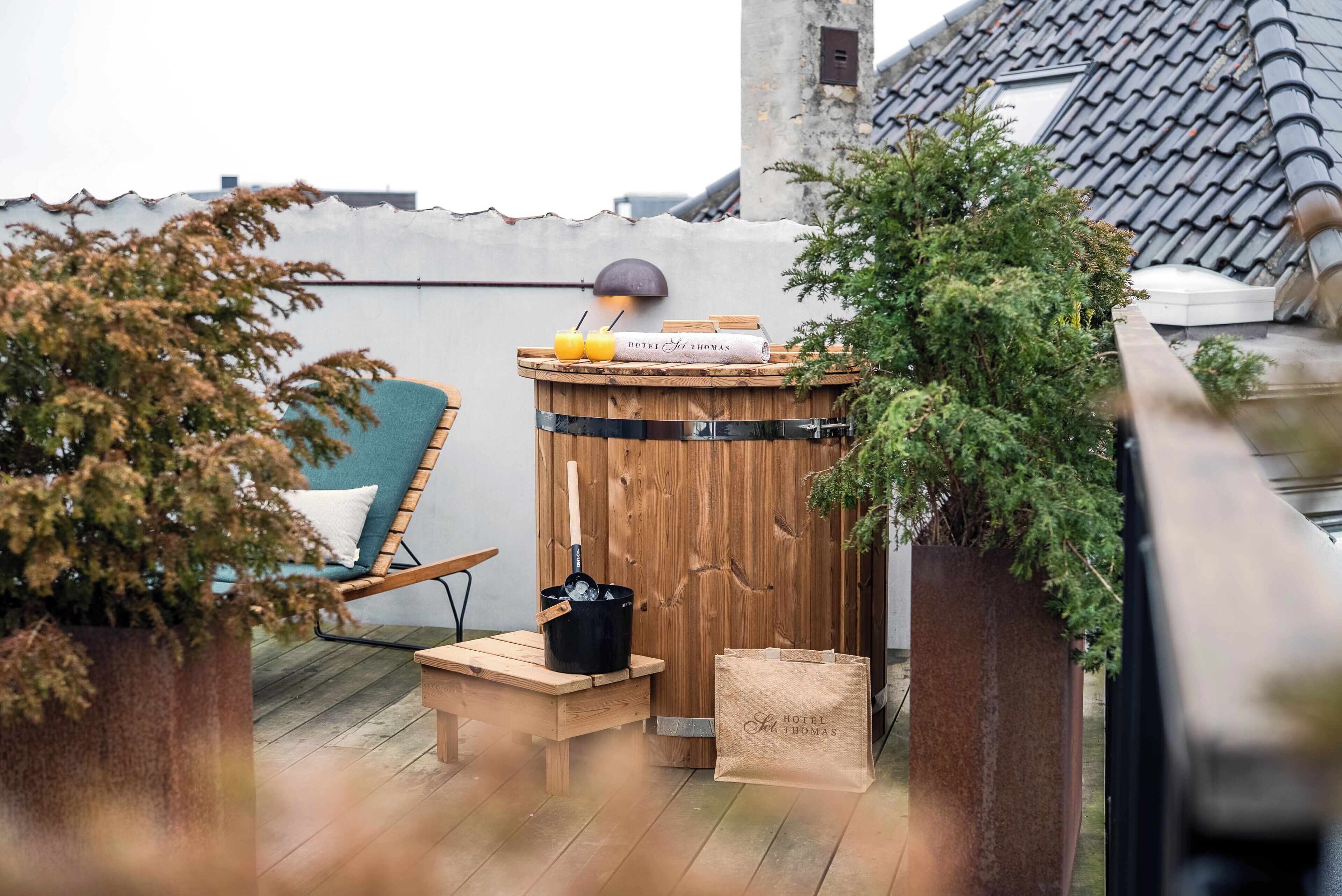 A wooden barrel with a sign, a wooden bench, a chair, a potted plant, and a bag of hotel stationery on a wooden deck.