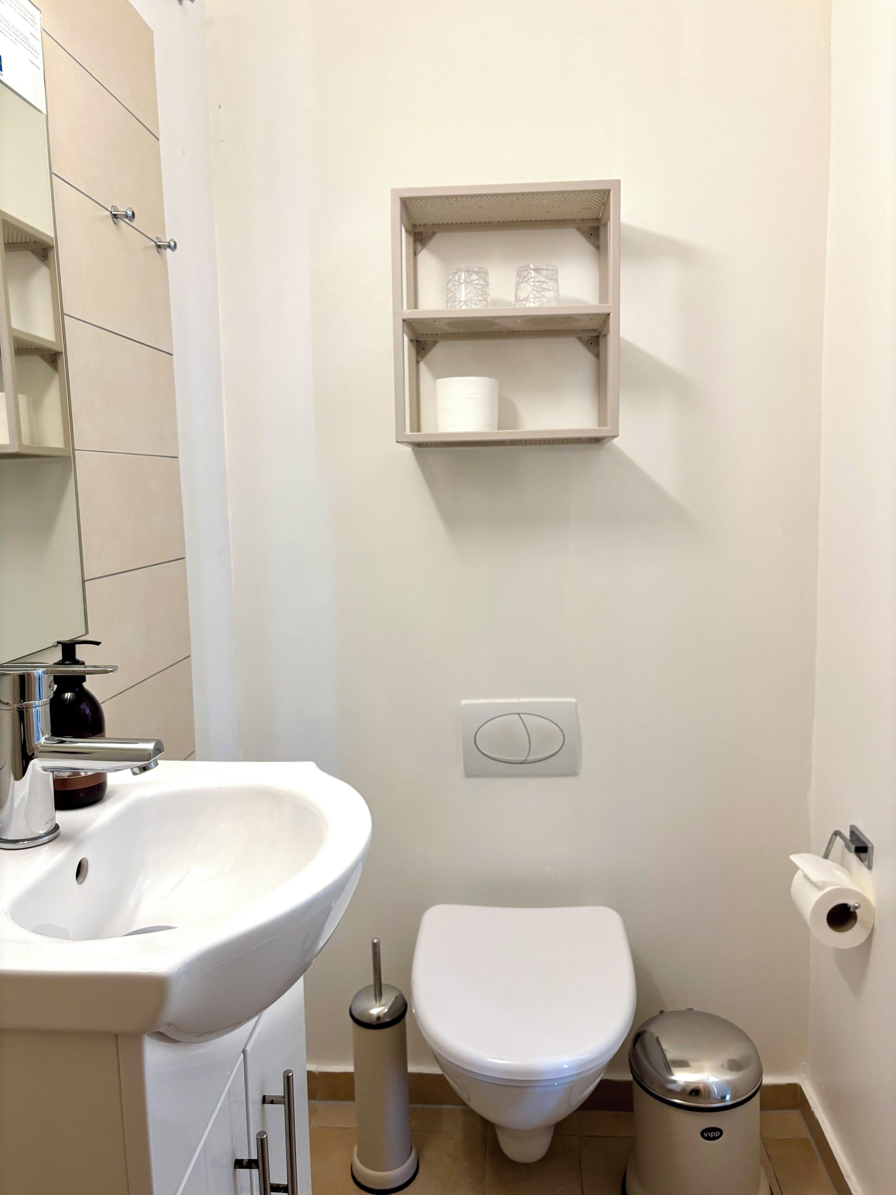 A bathroom with a white sink, toilet, and trash bin.